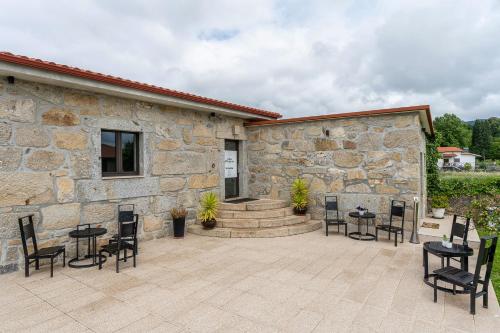 a patio with tables and chairs next to a stone building at Casa d'Amares in Amares