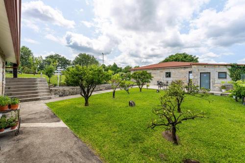 a green yard with trees in front of a building at Casa d'Amares in Amares