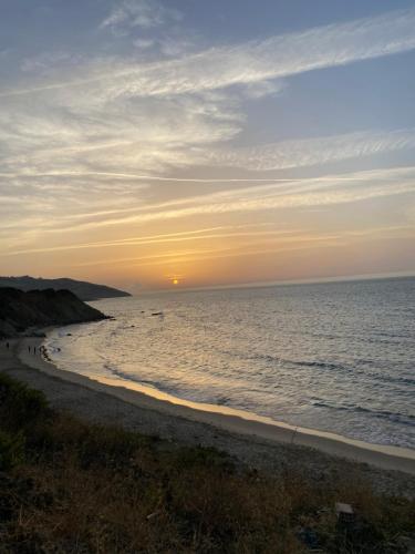 a sunset on a beach with the ocean at Séjour Bab Diki in Melîyech
