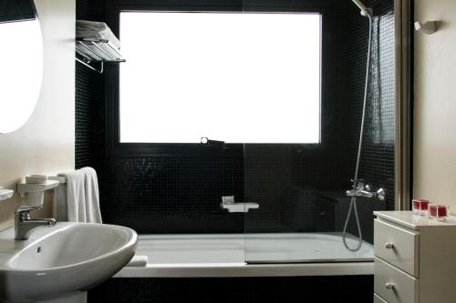 ein Badezimmer mit einem Waschbecken, einer Badewanne und einem Waschbecken in der Unterkunft Épico Recoleta Hotel in Buenos Aires