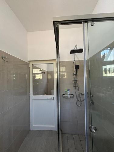 a bathroom with a shower and a glass door at Villa 176 in Baks-Rrjoll