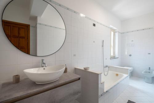 a white bathroom with a sink and a mirror at Luxury Domus Apartment in SantʼAgata di Militello