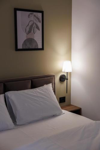 a bedroom with a bed with a white pillow and a lamp at Garni Hotel Maggitti in Velika Plana