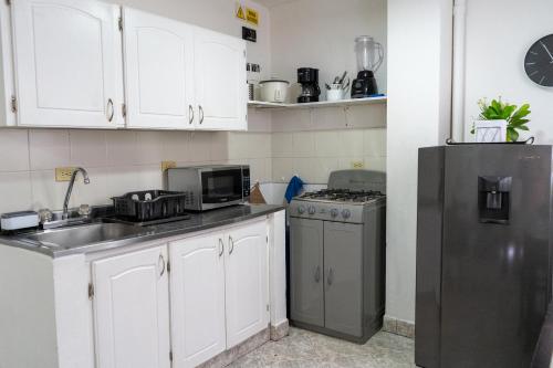 a kitchen with white cabinets and a black refrigerator at Apartamento Parque de Guatapé in Guatapé
