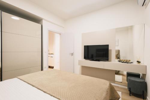 a white bedroom with a bed and a television at Dani Deluxe Apartments in Ulcinj