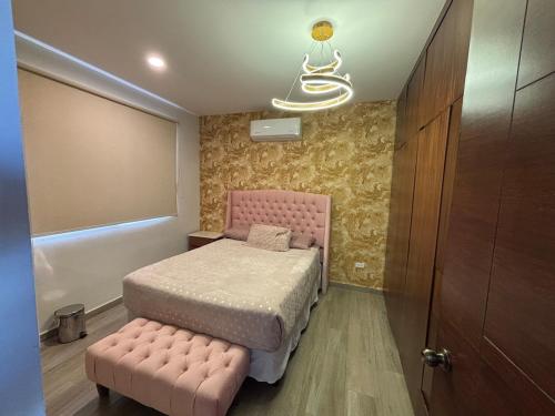 a small bedroom with a pink bed and a stool at Apartment with Excellent Ocean View, Terra 194 in Cabo San Lucas