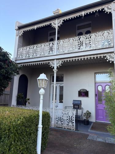 a white house with a balcony and a purple door at Purple Zebra Bowral in Bowral