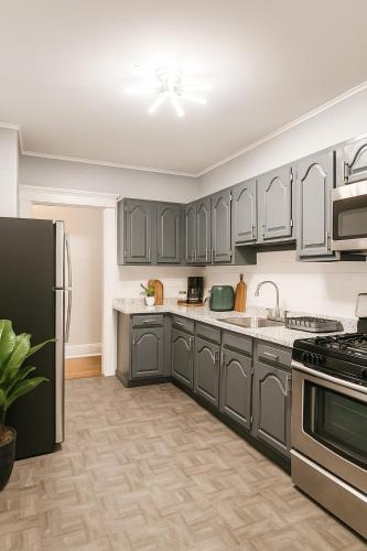 a kitchen with gray cabinets and stainless steel appliances at Spacious 4BR near NYC with Parking, 10min MetLife, 20min Times Sq in North Bergen