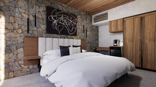 Un dormitorio con una gran cama blanca y una pared de piedra. en Finca N6 Hotel Boutique, en Ensenada