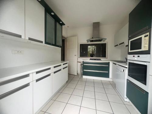 une cuisine avec des armoires blanches et des appareils verts et blancs dans l'établissement Maison typique Pyla proche plage, à La Teste-de-Buch
