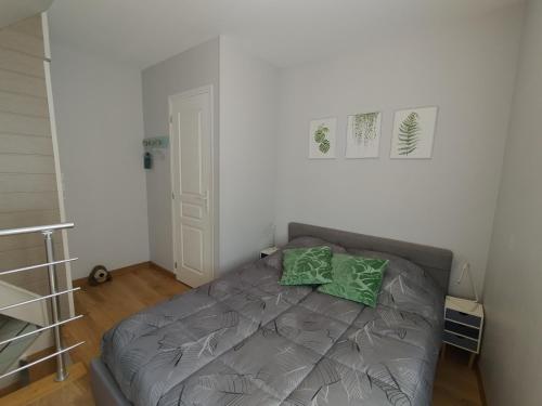 une chambre avec un lit avec deux oreillers verts dessus dans l'établissement Gîte LE BIVOUAC, à Fécamp