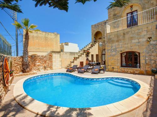 a swimming pool in front of a building at Villa Joy Farmhouse in Xagħra