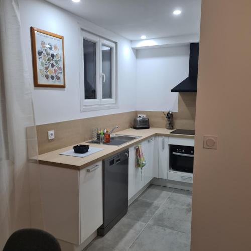 une cuisine avec des armoires blanches et un comptoir dans l'établissement Appartement Climatisé Nîmes, à Nîmes