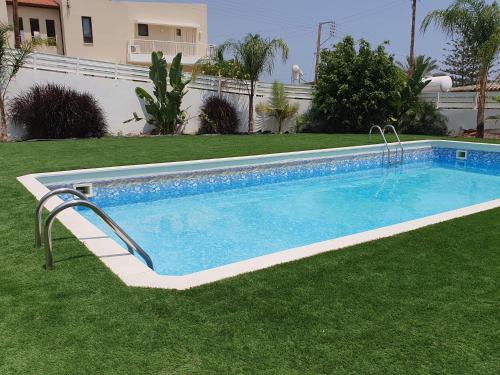 a large swimming pool in a yard with grass at Oroklini Hills in Voroklini