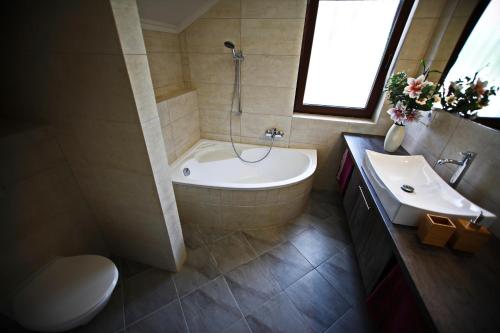 uma casa de banho com uma banheira, um WC e um lavatório. em Villamandala em Gyenesdiás