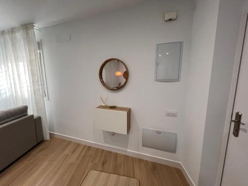 a white living room with a mirror and a couch at Apartamento Parque las Huertas Camposoto in San Fernando