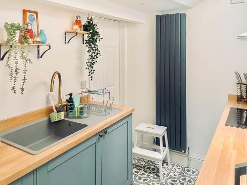 a kitchen with blue cabinets and a sink at Welsh Yard Cottage in Penrith