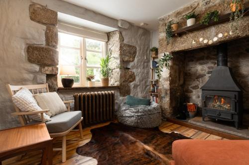 a living room with a stone wall with a fireplace at Idyllic hideaway with hot tub, gym & gamesroom in Penzance