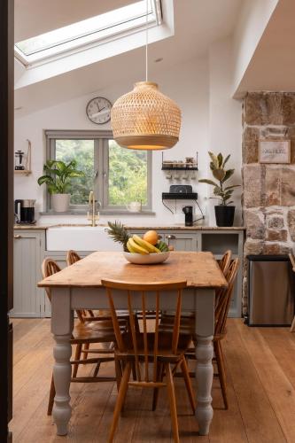a kitchen with a wooden table with a bowl of fruit on it at Idyllic hideaway with hot tub, gym & gamesroom in Penzance