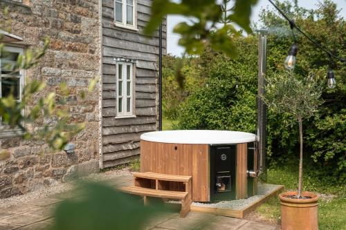 a bath tub sitting outside of a house at Idyllic hideaway with hot tub, gym & gamesroom in Penzance