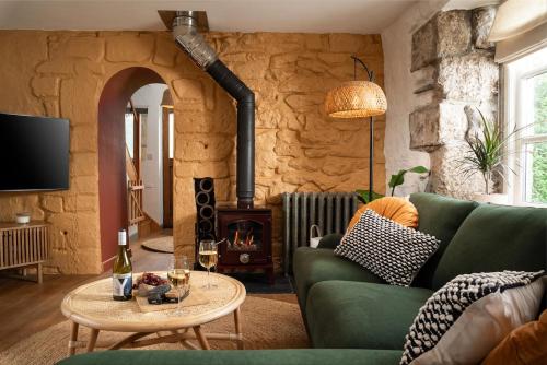 a living room with a green couch and a fireplace at Idyllic hideaway with hot tub, gym & gamesroom in Penzance