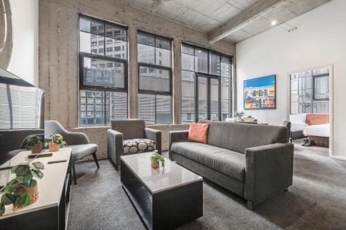 a living room with couches and tables and windows at Punthill Apartment Hotel - Manhattan in Melbourne