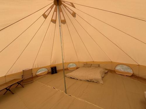 a tent with a bed in the middle of a room at Bell Tent 4m and 7m Fossewold Cotswold Camping in Moreton in Marsh