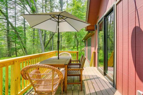 a wooden table and chairs with an umbrella on a porch at Waterfront Studio with Loft and Dock Near Narrowsburg! in Narrowsburg