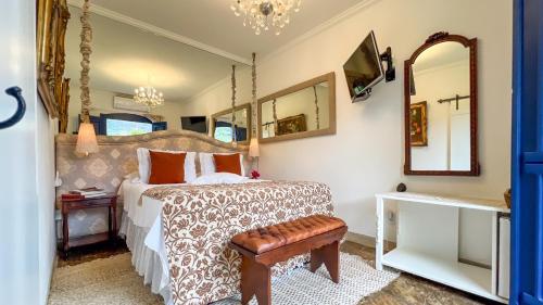 a bedroom with a bed and a mirror at Segredo da Serra Guest House in Tiradentes