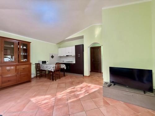 a living room with a flat screen tv and a kitchen at Casa Vacanze Sole in Monte Petrosu