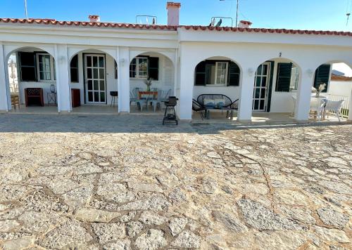 a white house with a large stone patio at Chalets con piscinas privadas junto al mar in Cala'n Bosch
