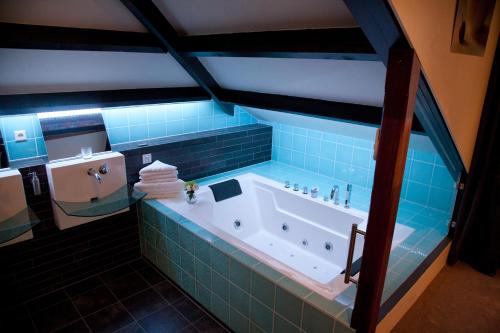 een badkamer met een bad met blauwe tegels bij Hotel-Restaurant Het Rechthuis in Muiderberg
