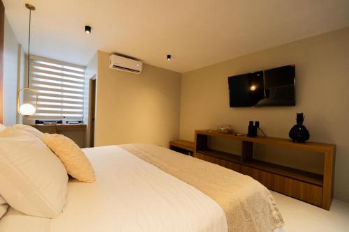 a bedroom with a white bed and a flat screen tv at Casa Mía Hotel Boutique in Zamora de Hidalgo