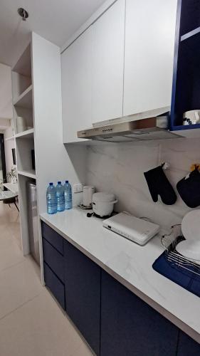 a kitchen with white cabinets and bottles of water at Blue Belle Staycation Pollux Habibie in Batam Center