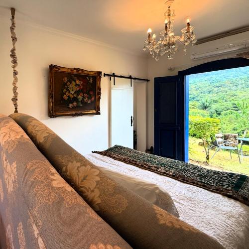 a bedroom with a bed with a window and a chandelier at Segredo da Serra Guest House in Tiradentes
