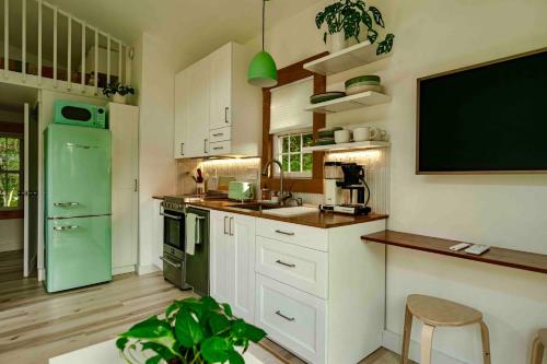 a kitchen with a green refrigerator and white cabinets at Red Barn Cabin Near Okemo in Brownsville