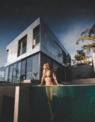 a woman in a bikini standing in a swimming pool at Saudade Residence - Ultra Luxury Futuristic Ocean Zen Retreat in Ribeira Brava