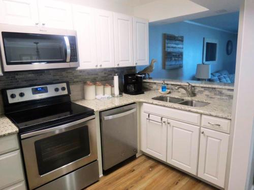 a kitchen with a stove and a sink and a microwave at Mariner East in Panama City Beach