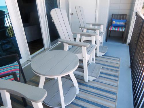a row of white chairs and a table on a porch at Mariner East in Panama City Beach