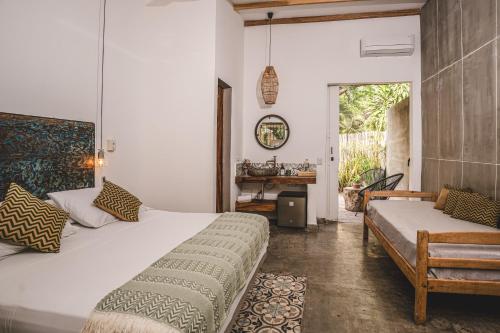 a bedroom with a large white bed and a bench at Waka Hotel Rural in Honda