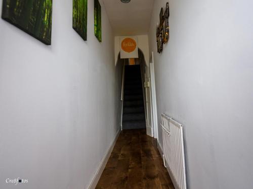 a hallway with white walls and wooden floors at Bucknall Lodge Hanley Family Room 4 in Stoke on Trent