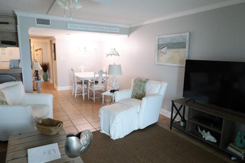 a living room with white chairs and a flat screen tv at Mariner East in Panama City Beach