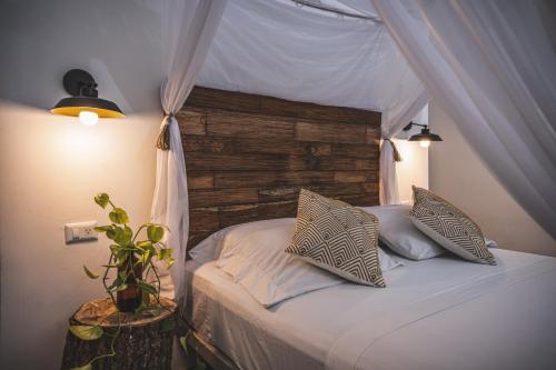 a bedroom with a canopy bed with a plant on a table at Waka Hotel Rural in Honda