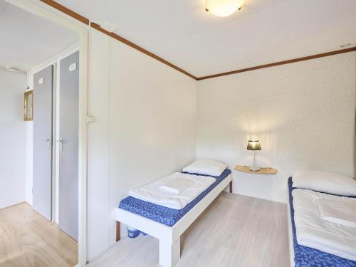 ein kleines Zimmer mit 2 Betten und einer Lampe in der Unterkunft Kerkuil in Hulshorst