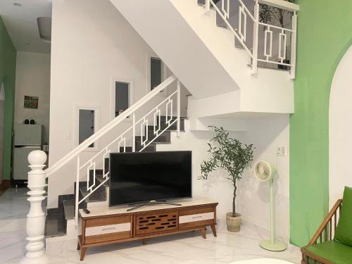 a living room with a tv and a staircase at Nai's House in Hue