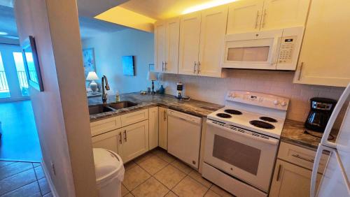 a kitchen with white cabinets and a stove and microwave at Mariner East in Panama City Beach
