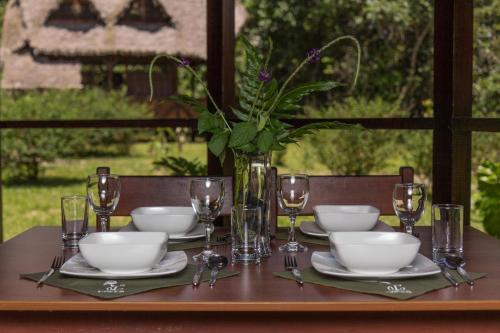 a table with plates and glasses and a vase with flowers at Ecotone Manu Learning Center, All-Inclusive in Pillcopata