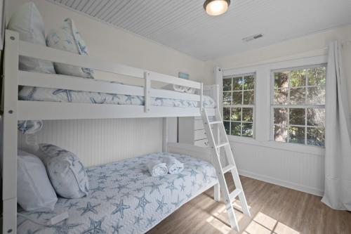 een slaapkamer met een stapelbed en een ladder bij Beachside Cottage - Pet Friendly in Oak Island