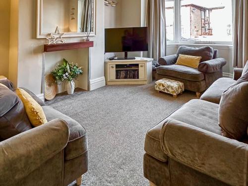a living room with two couches and a television at Number Five in Filey