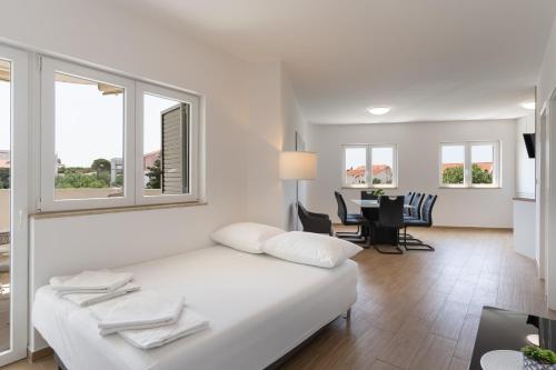 a white bedroom with a bed and a dining room at Apartment Paula in Novalja